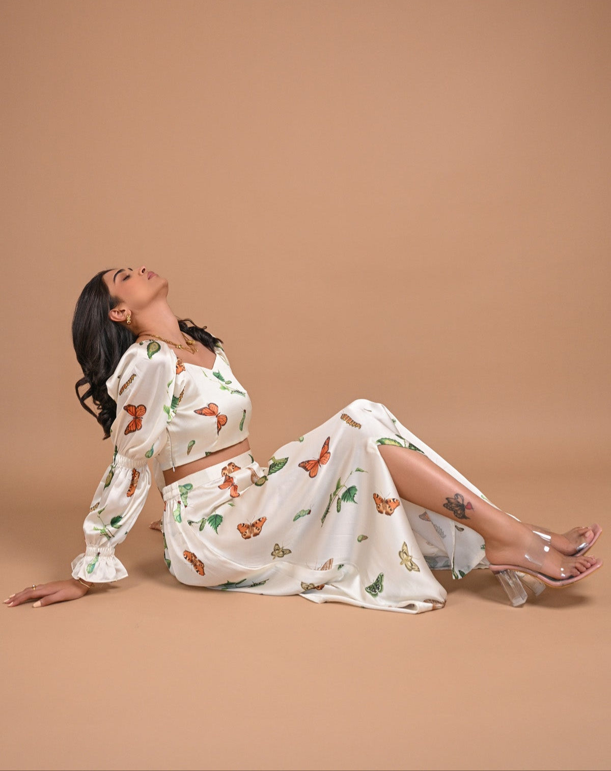 Woman in a butterfly-patterned dress sitting on a beige background